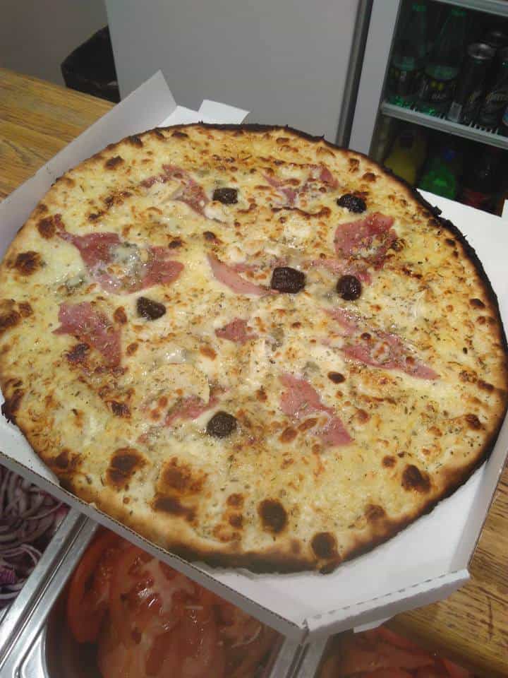 Pizza blanche au jambon cru et aux olives dans sa boîte