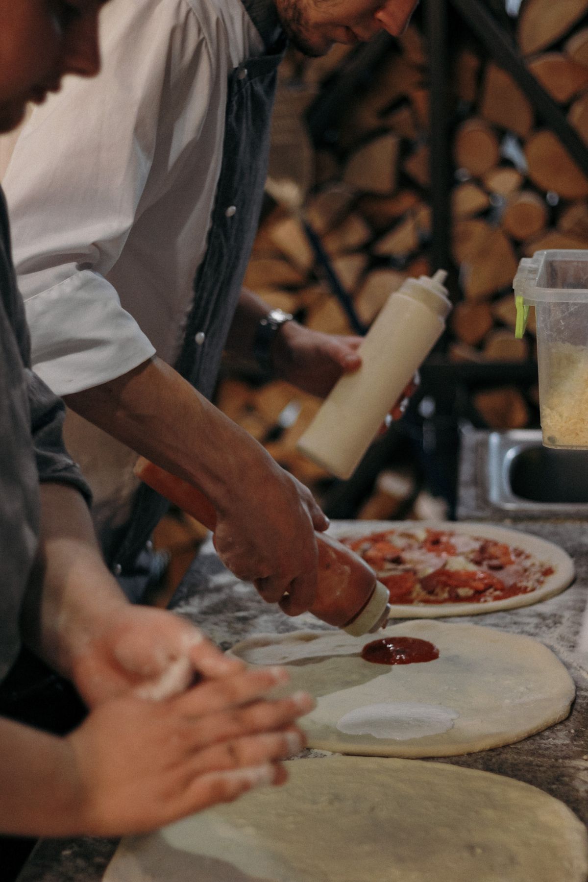 Mains qui étalent la pâte et garnissent des pizzas
