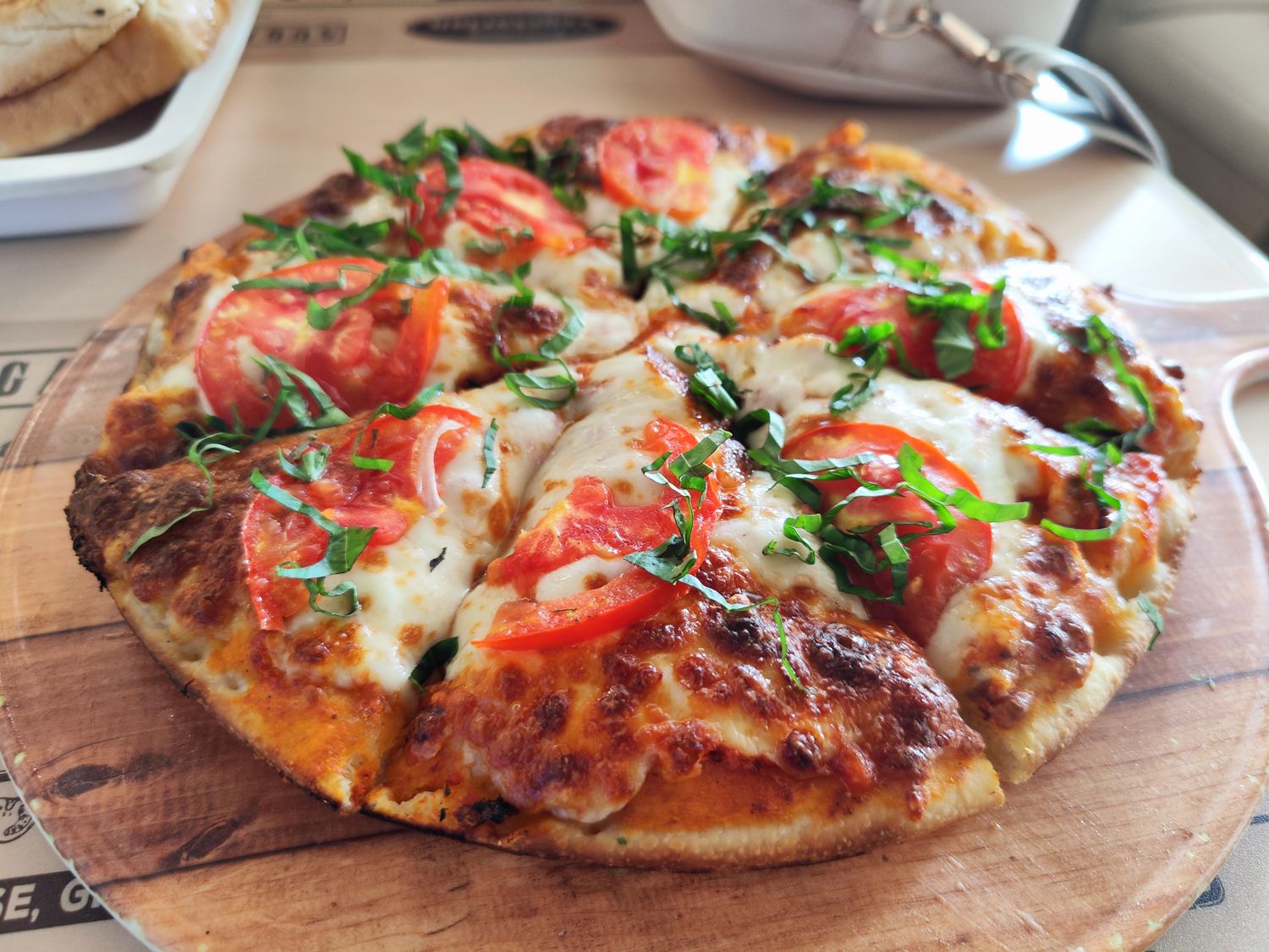 Pizza à la tomate fraîche et au basilic sur planche de bois